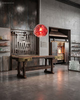 Copper molten pendant hanging in a raw concrete kitchen with a timber worktable