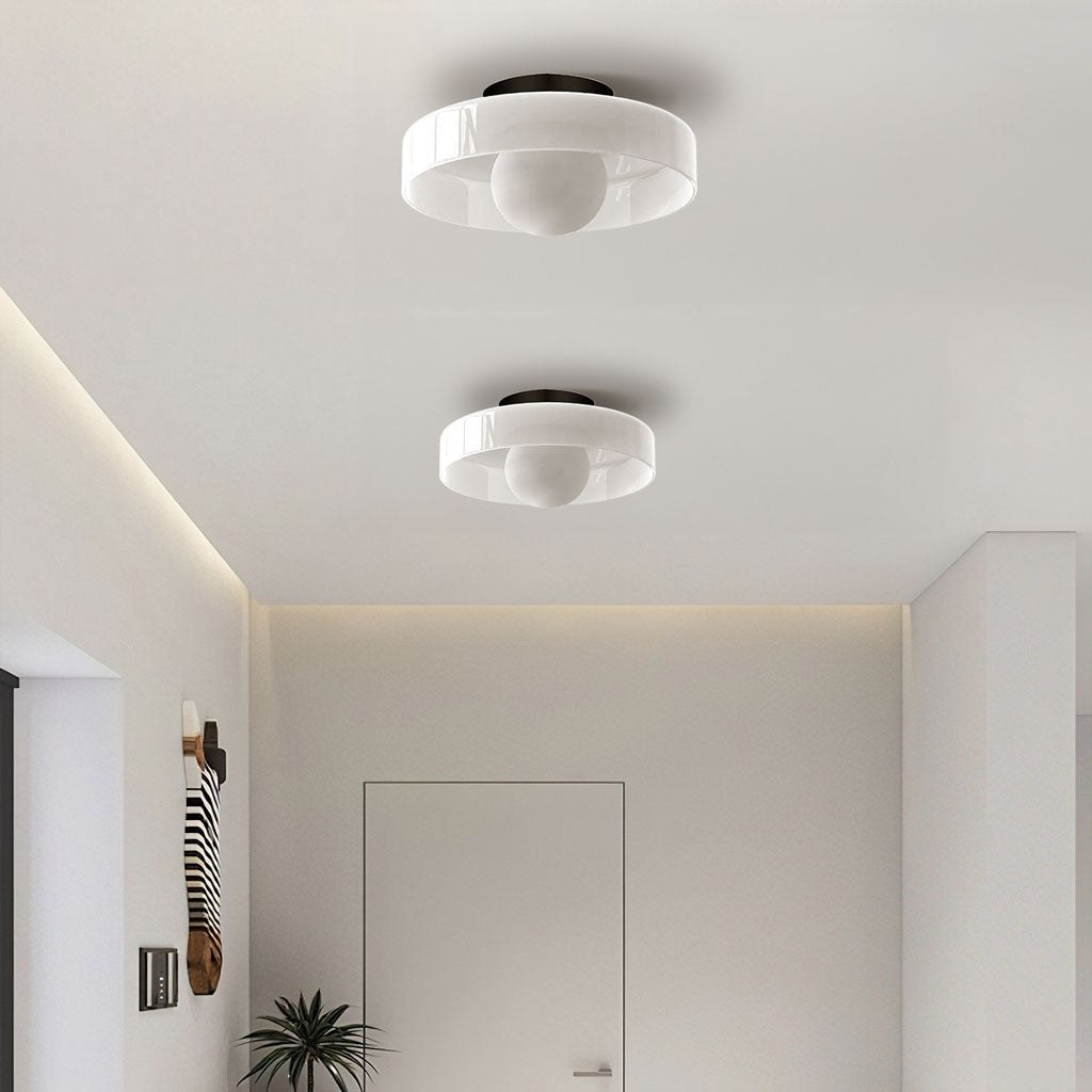 White glass disc ceiling light lit warmly