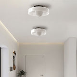White glass disc ceiling light lit warmly