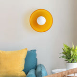 Orange glass disc wall light glowing softly
