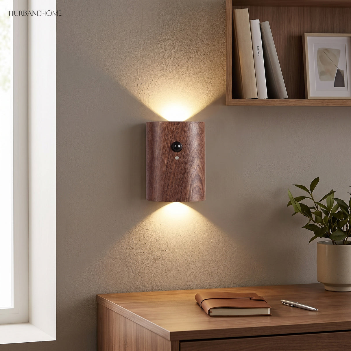 Dark wood sensor wall light lit above a desk beside a window