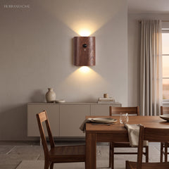 Dark wood sensor wall light lit on a wall beside a dining table
