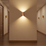 Wood sensor wall light lit on a plain wall in a hallway