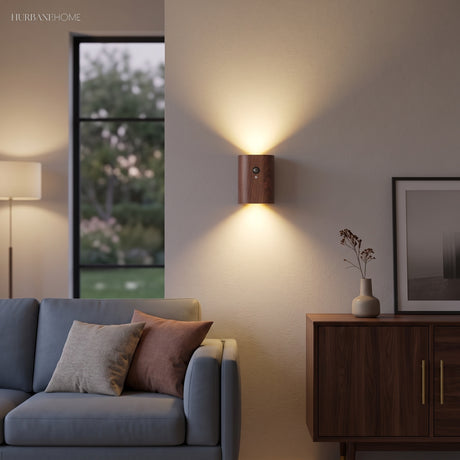 Dark wood sensor wall light lit above a blue sofa and sideboard