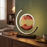 Red moving sand art LED table lamp on wooden sideboard, black frame