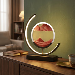 Red moving sand art LED table lamp on wooden sideboard, black frame