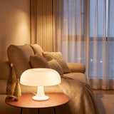 White mushroom table lamp lit on a side table next to a linen sofa