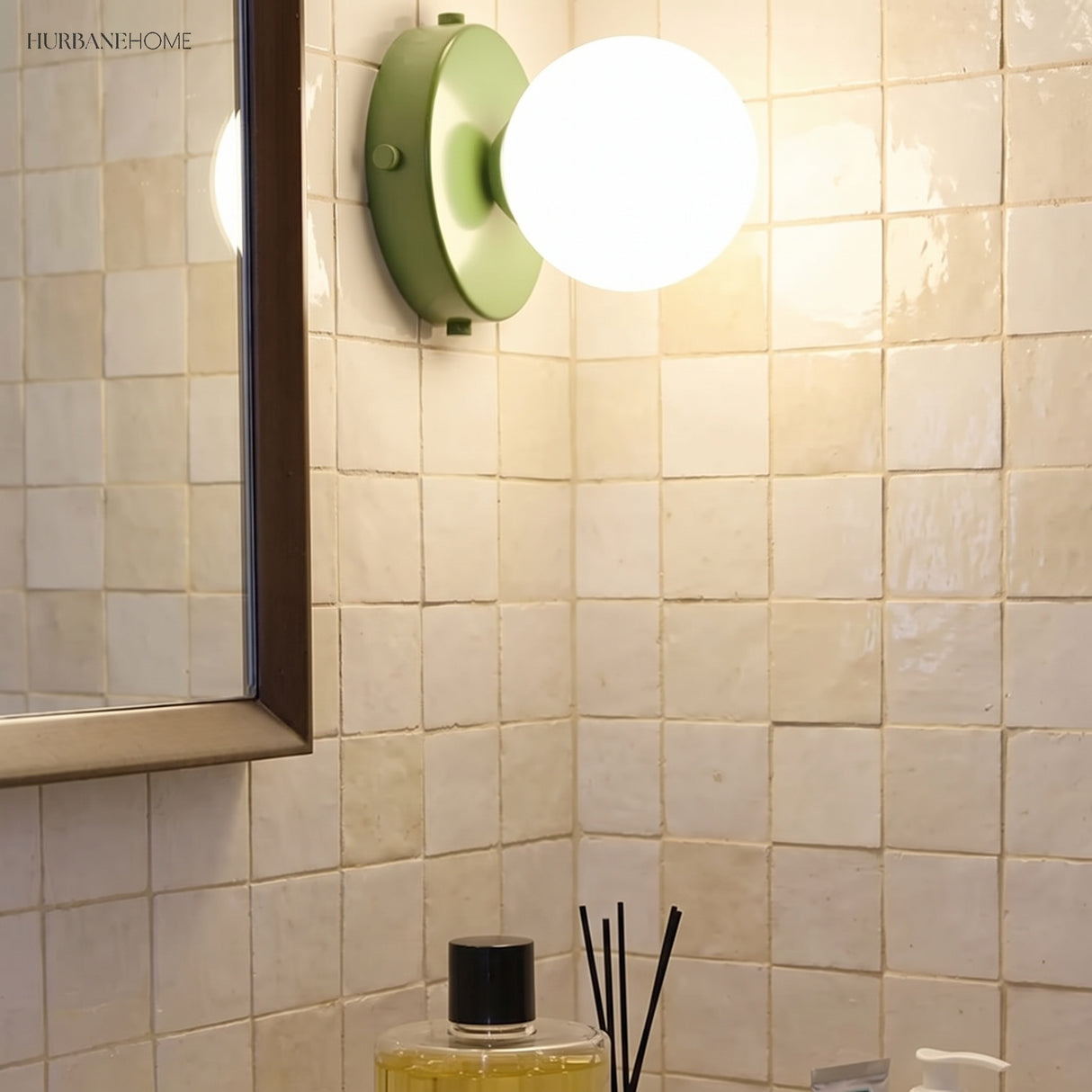 Green glass globe wall lamp on a tiled bathroom wall beside a mirror