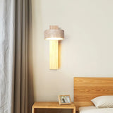 Natural wood travertine wall sconce beside a curtain above a bedside table