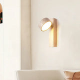 Natural wood sconce with shade rotated down to light a wall above a sofa