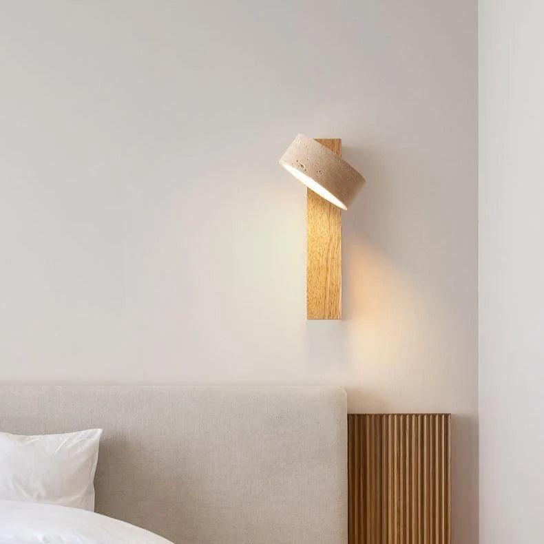 Natural wood sconce with tilted travertine shade above a slatted bed headboard