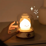 Fingertips reaching toward the clear dome of the lit flame night light