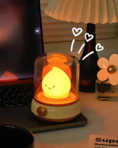 Night light showing a deep amber glow on a desk beside a pleated shade lamp