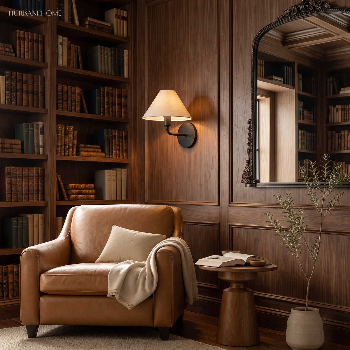 Fabric cone sconce on walnut bookshelves above a tan leather armchair