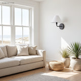 Black cone wall sconce in a bright coastal living room by a window