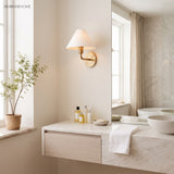 Brass cone wall sconce above a stone bathroom vanity and potted tree