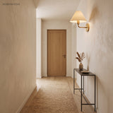 Brass fabric cone sconce lighting a plain plaster hallway and console