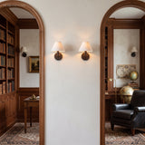 Two fabric cone sconces between arched openings in a panelled library