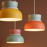 Three lit colorful pendant lights against a brown studio backdrop