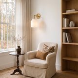 Minimalist glass dome sconce beside a bookcase and armchair in daylight