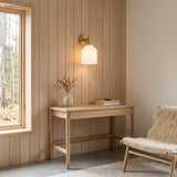 Nordic wall sconce on timber panelling above a slim writing desk