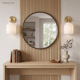 Pair of glass dome sconces flanking a round mirror on fluted wood