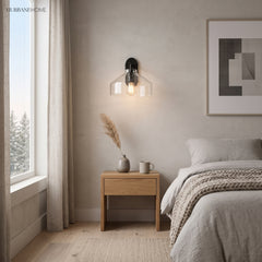 Clear glass sconce with black fitting above a bedroom nightstand