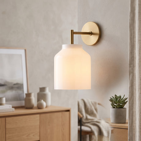 Brass arm wall sconce with milk glass dome shade above an oak sideboard