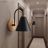 Black cone shade sconce on a wood mount lit in a corridor