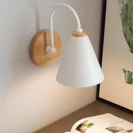 White cone shade sconce on a wood mount lit beside a framed print