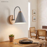 Grey cone shade sconce lit above a dining table and plant