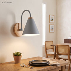 Grey cone shade sconce lit above a dining table and plant