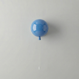 Blue balloon light mounted on a white wall with a hanging cord