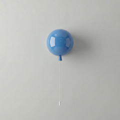 Blue balloon light mounted on a white wall with a hanging cord