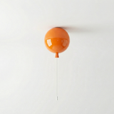Orange balloon light fitted to a ceiling above a plain wall