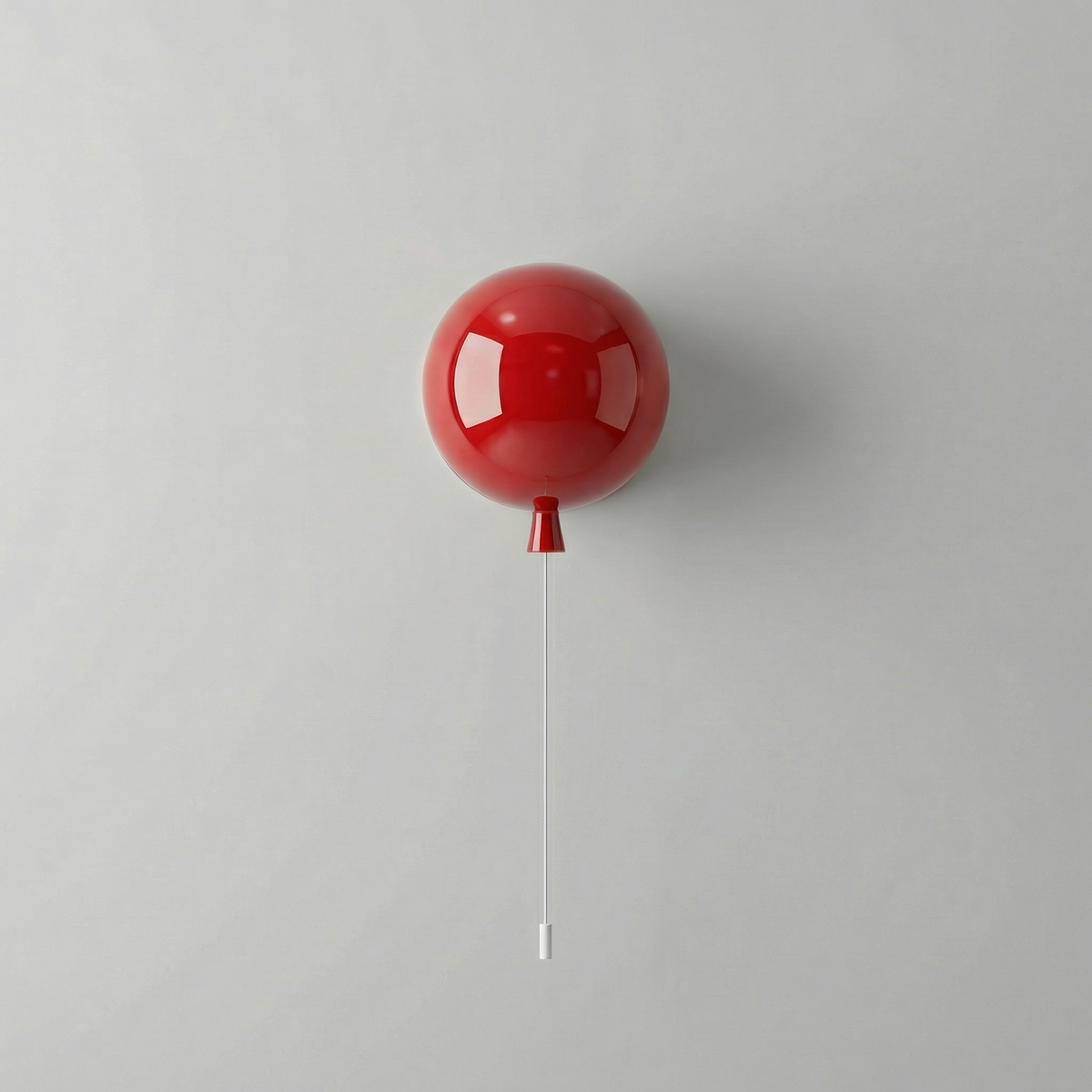 Small red balloon light on a plain wall with its pull cord