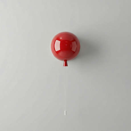 Small red balloon light on a plain wall with its pull cord