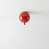 Red balloon light lit on a white wall with a hanging pull cord