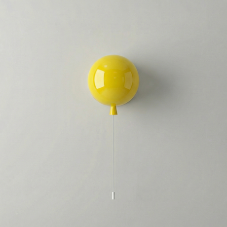 Yellow balloon light on a white wall with a long pull cord