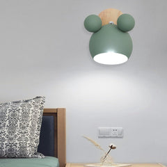 Green mouse wall light lit above a bed with a patterned cushion