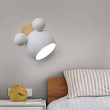 Pale grey mouse wall light lit above a bed with striped bedding