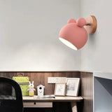 Pink mouse wall light lit above a desk with books and a small house
