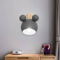 Grey mouse wall light lit above a sideboard beside a picture frame