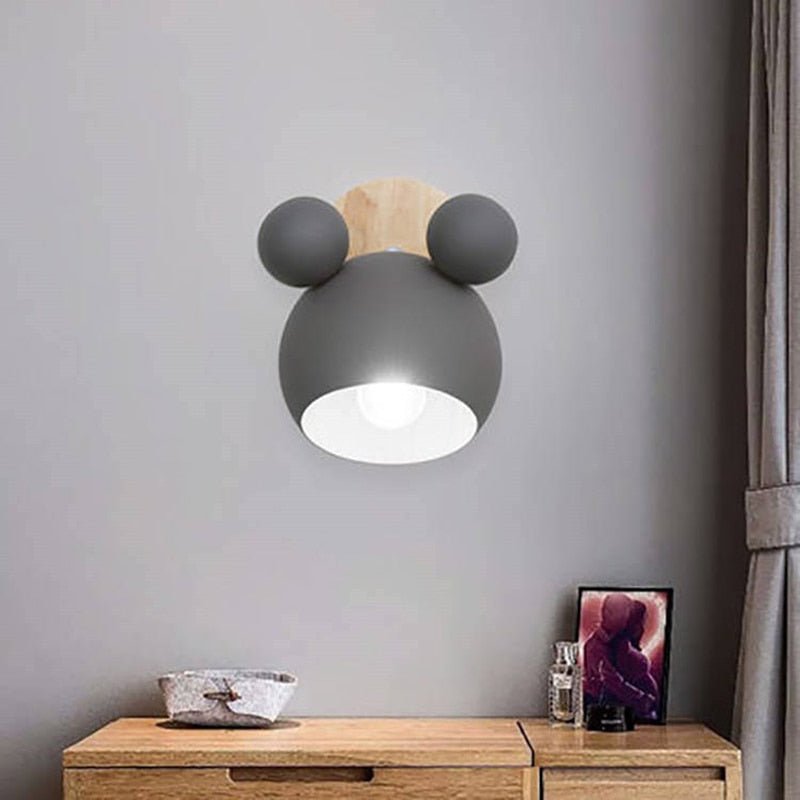 Grey mouse wall light lit above a wooden sideboard and framed photo