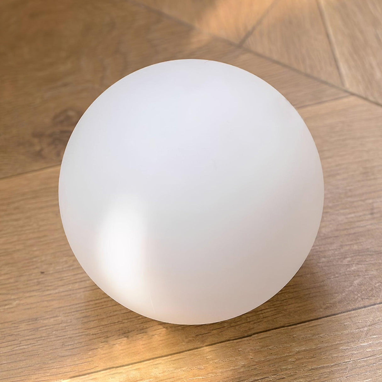 Single opal glass globe photographed resting on a timber floor