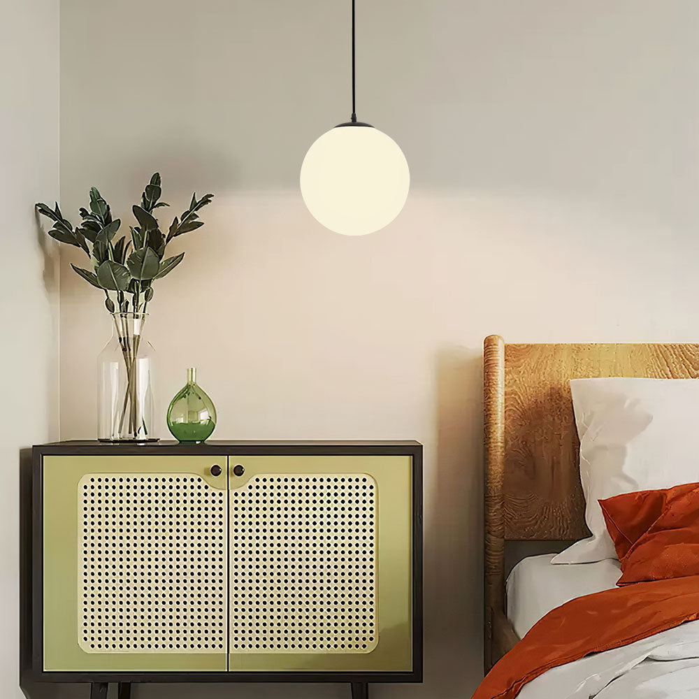 Opal glass globe pendant above a rattan fronted sideboard in a bedroom