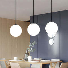 Three opal glass globe pendants above a light timber dining table