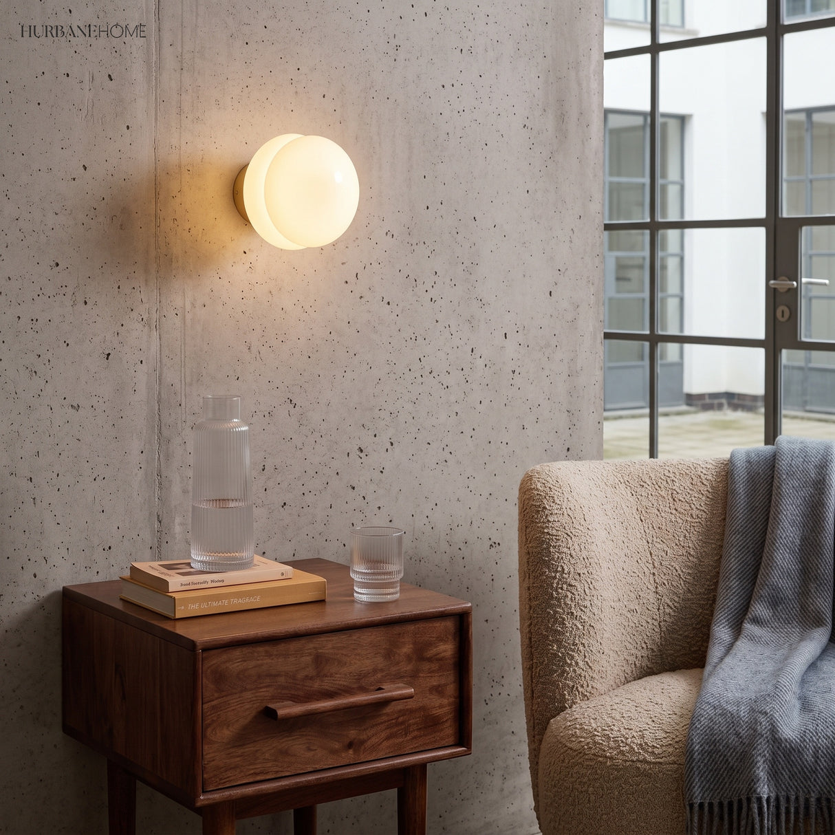 White opal glass wall sconce mounted above a walnut bedside table