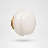 White opal glass wall sconce on a brushed brass round backplate
