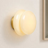 Pale cream glass wall sconce beside a framed mirror edge